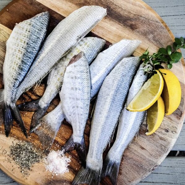 pescado fresco y limón en un plato de madera